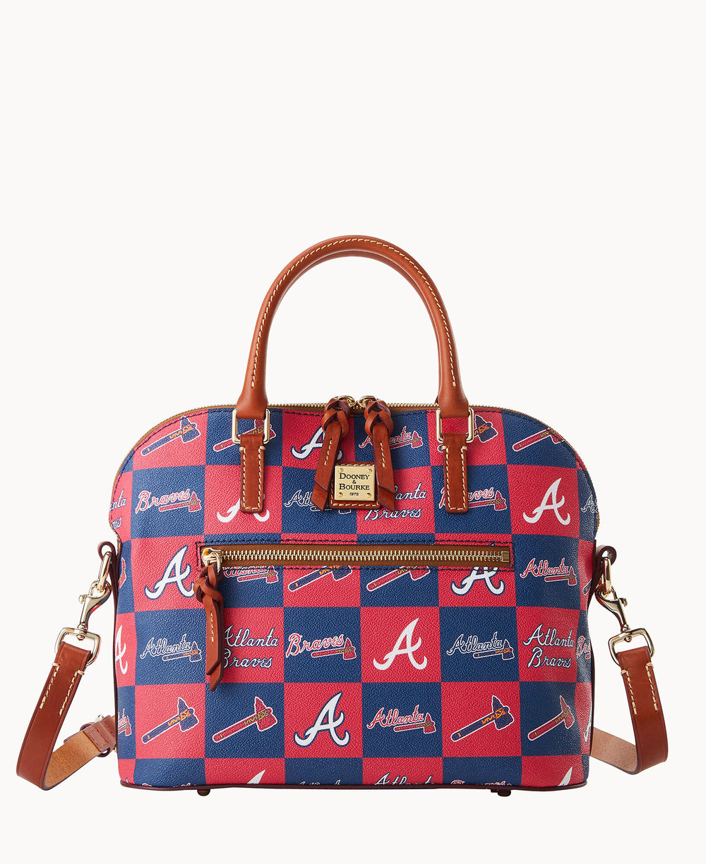 A red and blue Dooney & Bourke handbag featuring Atlanta Braves logos, text, and tomahawk graphics, with brown leather handles, trim, and a detachable shoulder strap.