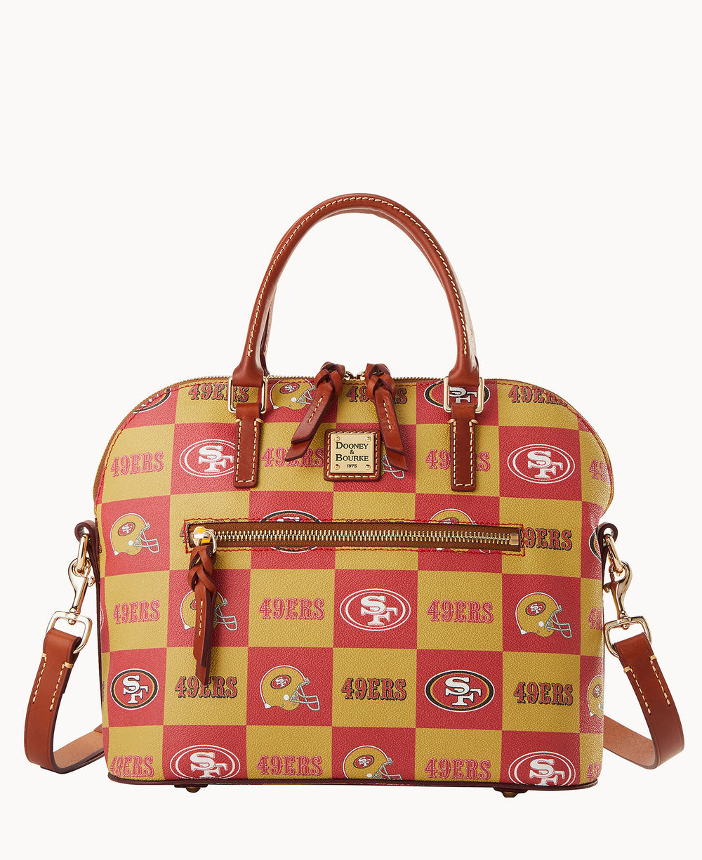 A handbag with brown leather handles and trim, featuring a red and gold checkerboard pattern with the San Francisco 49ers logo and 49ERS text. The bag has a front zipper pocket and a detachable shoulder strap.