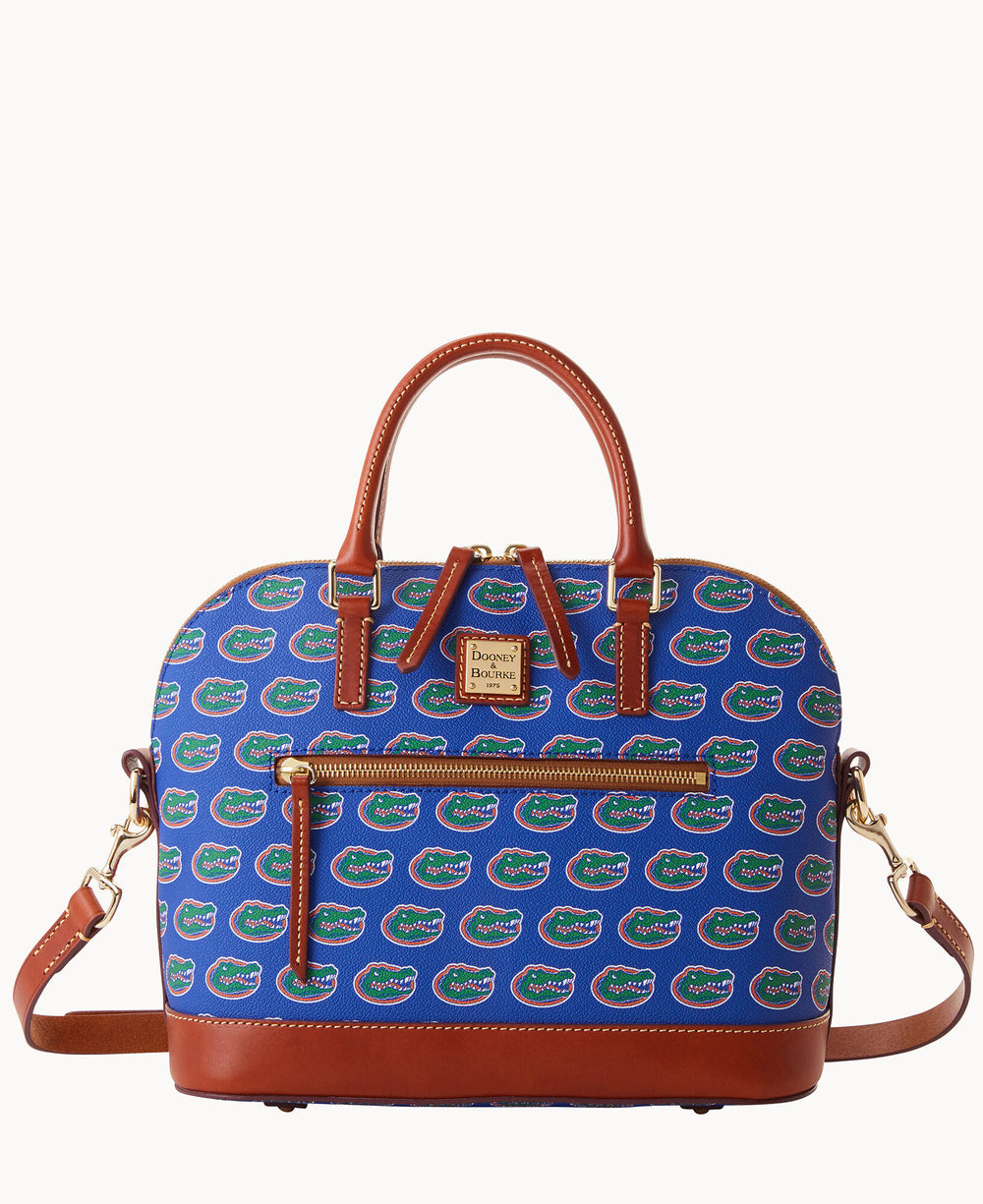 A blue satchel handbag with brown leather handles and trim, gold-tone hardware, a front zipper pocket, and a repeating pattern of green, orange, and white alligator logos.