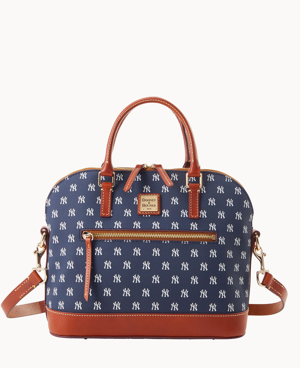 A navy blue and brown leather handbag with double handles, a detachable shoulder strap, a front zip pocket, and an all-over white New York Yankees logo print.