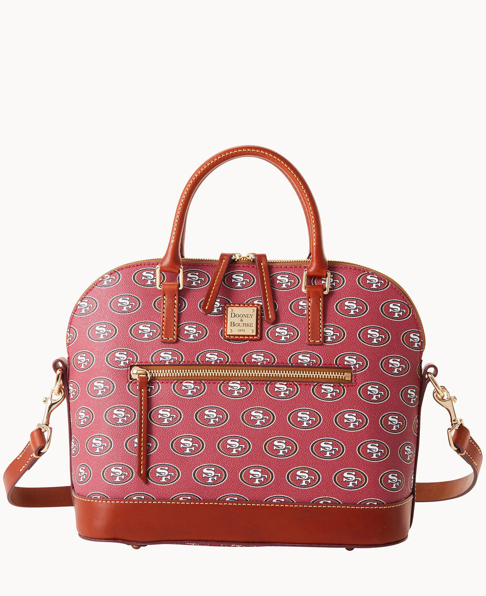 A red handbag with brown leather handles and trim, featuring an all-over repeating San Francisco 49ers logo pattern, a front zipper pocket, and a detachable shoulder strap.