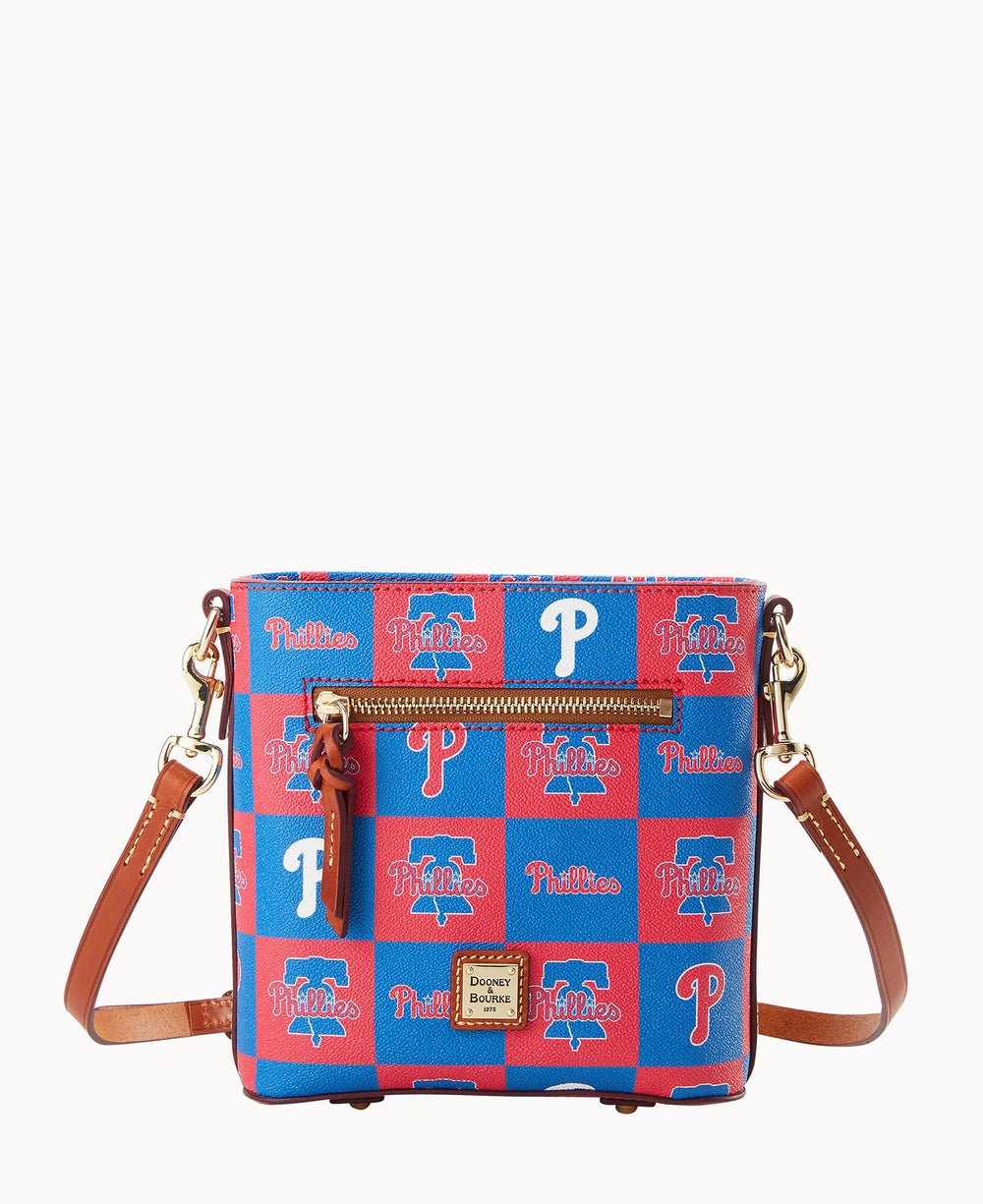 A blue and red crossbody bag with brown leather straps, decorated with Philadelphia Phillies logos and patterns, and a front zipper pocket.