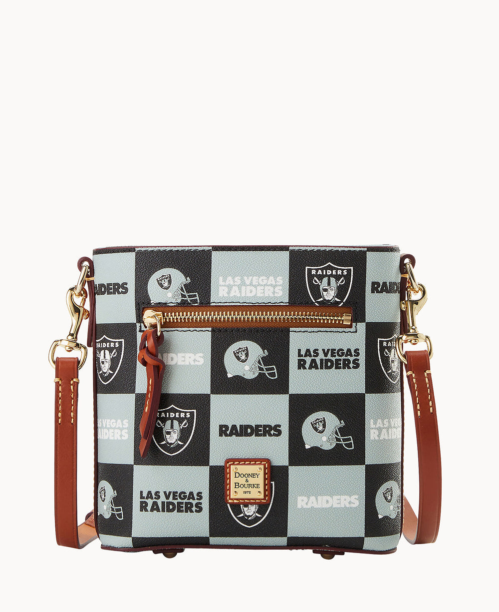Square crossbody bag with brown leather strap and trim, featuring a checkerboard pattern of Las Vegas Raiders logos and text. Front zip pocket and a Dooney & Bourke logo patch at the bottom center.