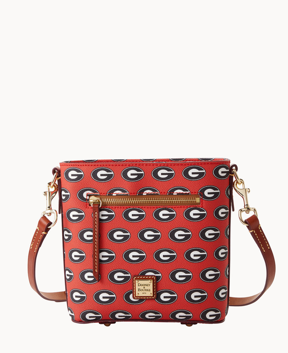 A red crossbody bag with brown leather straps, gold hardware, and a front zipper. The bag features a repeating black G logo pattern and a gold Dooney & Bourke label at the bottom center.