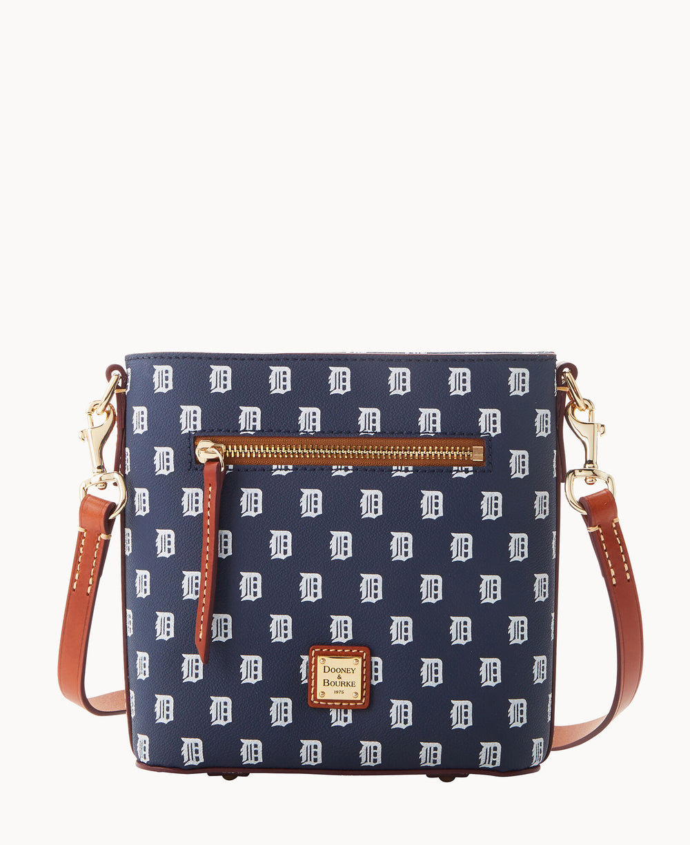 A navy blue crossbody bag with brown leather straps, gold hardware, a front zip pocket, and a repeating white D pattern. The bag has a small rectangular Dooney & Bourke logo patch on the front.