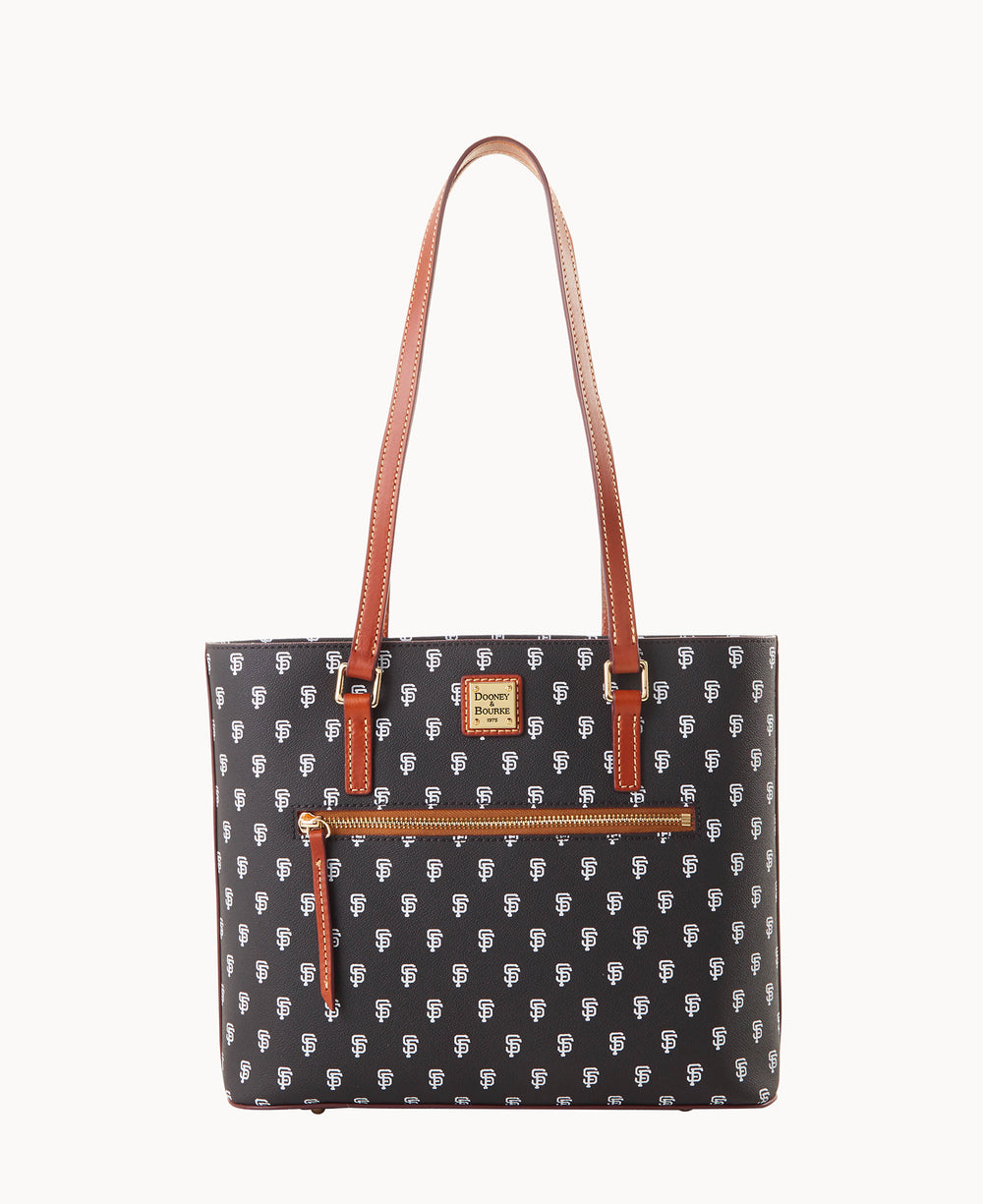 A black tote bag with brown leather straps and trim, a front zip pocket, and a repeating white â€œSFâ€ logo pattern. The bag also features a small gold and brown brand plaque on the front.