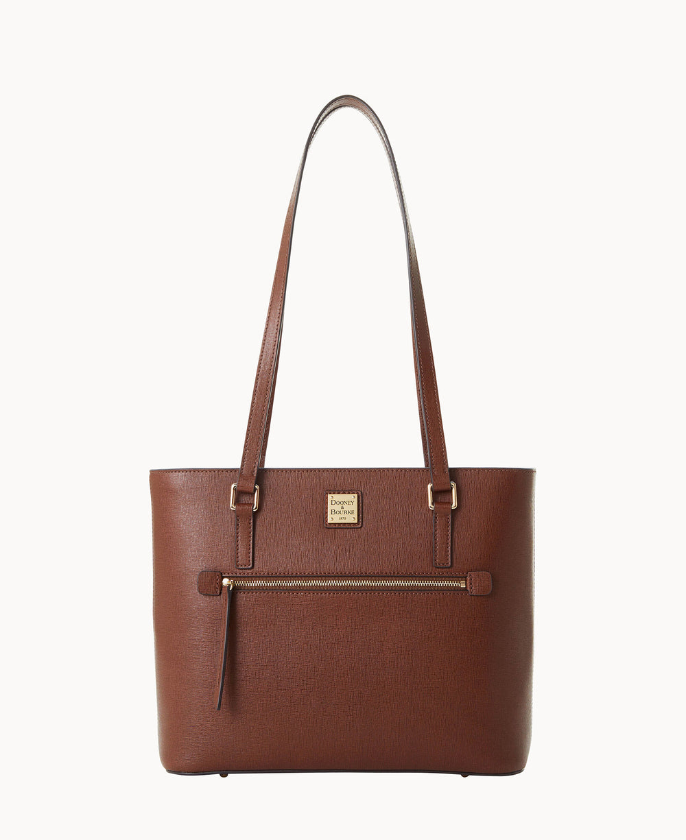 A brown leather tote bag with two shoulder straps, a front zippered pocket, and a gold-toned brand logo plate above the pocket, set against a plain white background.
