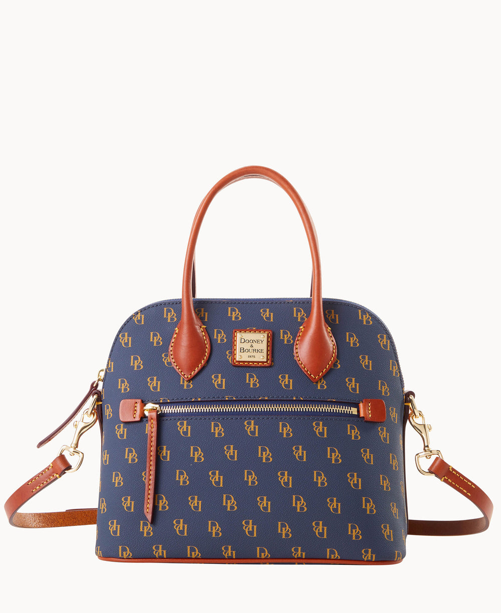 A structured blue handbag with brown leather handles and trim, featuring a repeating DB monogram pattern, a front zipper pocket, gold hardware, and a detachable shoulder strap.