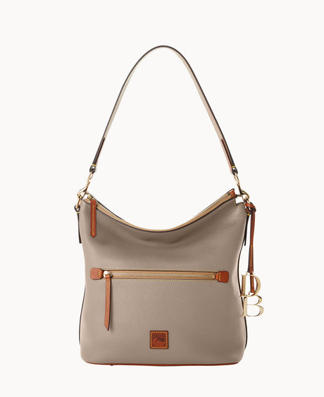 A taupe leather shoulder bag with a front zip pocket, gold hardware, brown trim, and a keychain featuring gold DB initials hanging from a leather strap.