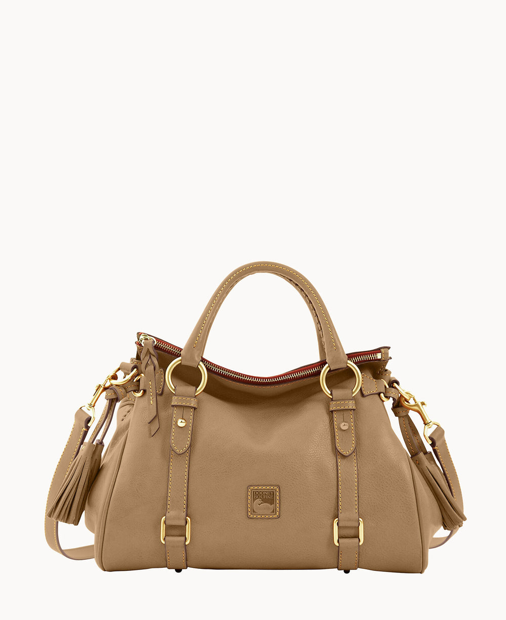A tan leather handbag with double handles, gold-tone hardware, a top zipper, a tassel detail, and a detachable shoulder strap, displayed against a plain white background.