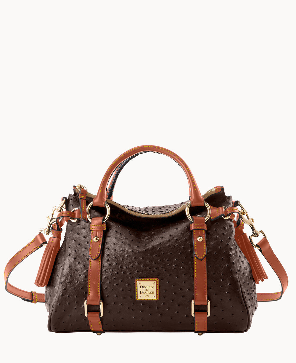 A dark brown textured leather handbag with tan leather handles, gold hardware, and a detachable shoulder strap. The front features a gold square Dooney & Bourke logo and two vertical leather straps with buckles.