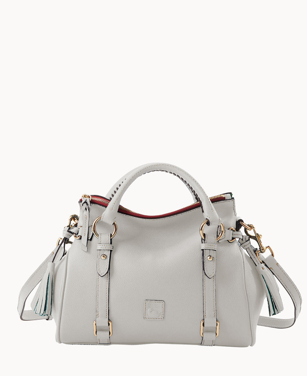A light gray leather handbag with gold hardware, double handles, a detachable shoulder strap, decorative tassels, and a zippered top accented with a hint of red lining.