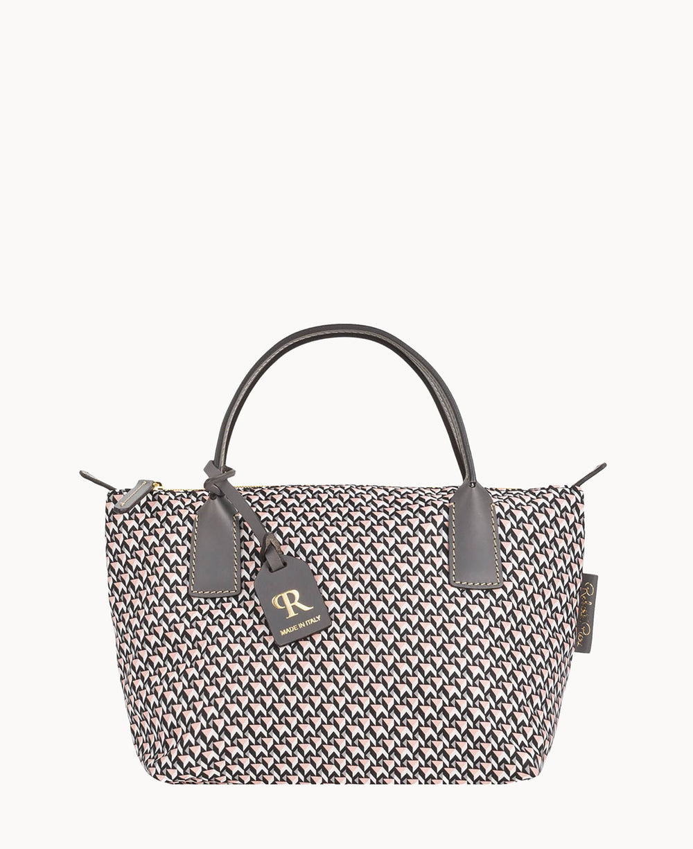 A stylish handbag with a black, white, and pink geometric pattern, featuring black leather handles and a black tag with gold lettering attached to one handle.