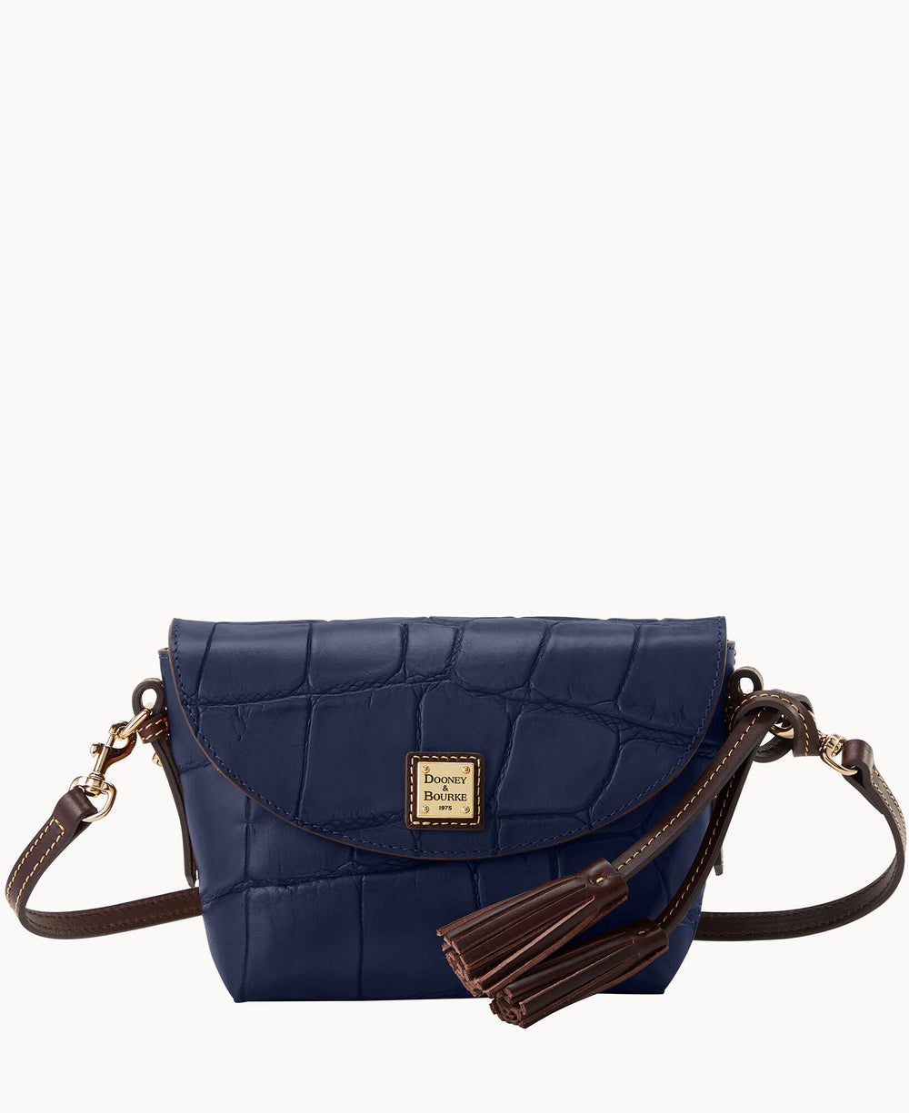 A small navy blue crossbody bag with a crocodile texture, brown leather strap, gold hardware, and tassel accents. The front features a gold Dooney & Bourke logo plate.