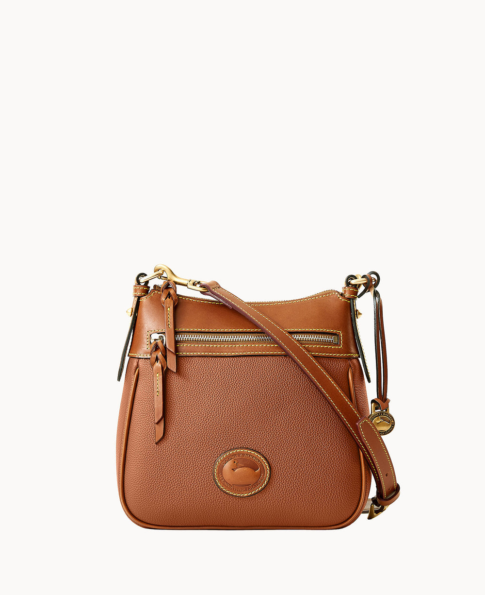 A brown leather crossbody bag with a front zipper pocket, gold hardware, and an adjustable strap. The bag features a rounded rectangular shape and a circular logo patch on the front.