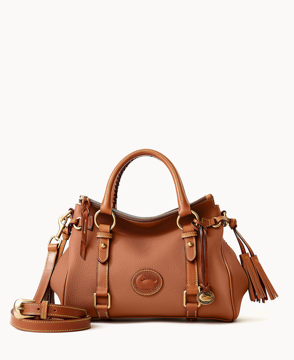 A brown leather handbag with double handles, gold-tone hardware, a detachable shoulder strap, buckle accents, tassel detail, and a circular logo on the front. The bag is set against a plain white background.