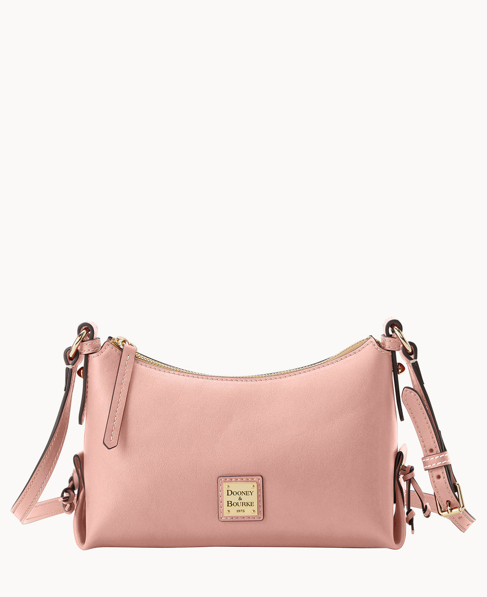 A small, blush pink leather crossbody bag with a gold-toned zipper, adjustable strap, and a gold Dooney & Bourke logo plate on the front.