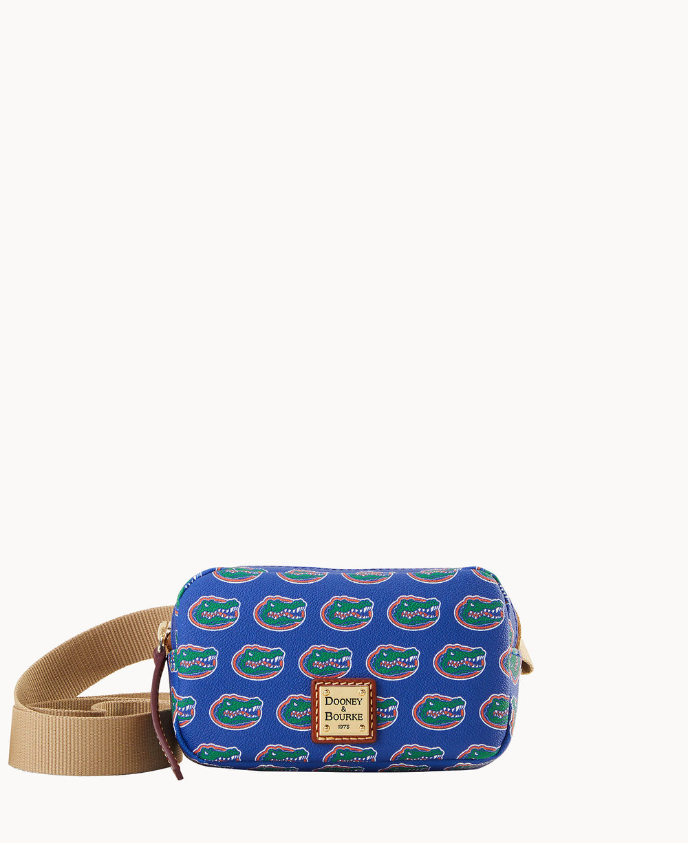 A small blue crossbody bag with an adjustable tan strap, decorated with repeating University of Florida Gators logos and a Dooney & Bourke label on the front.