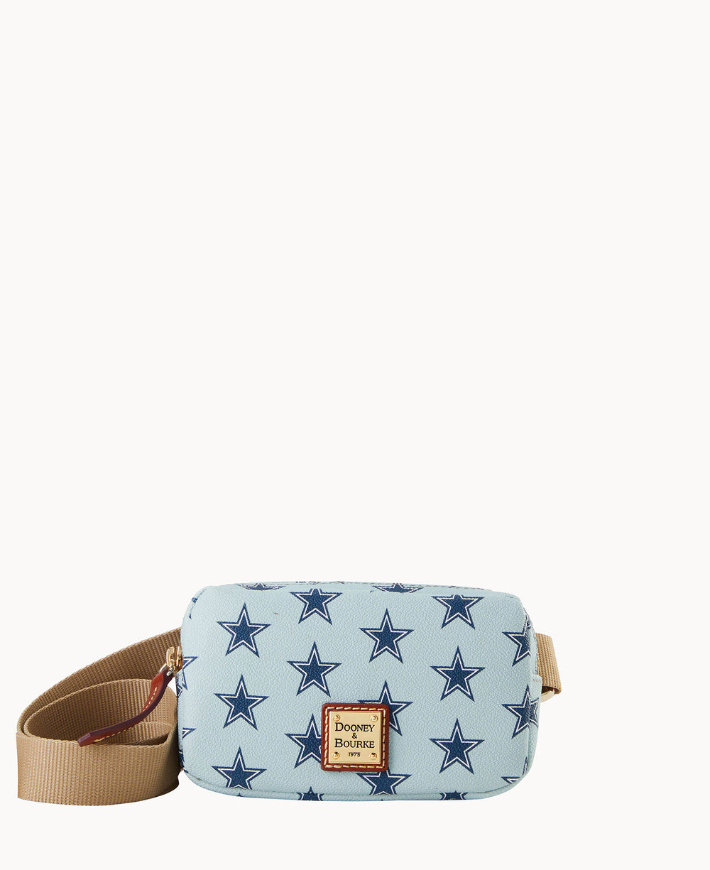 A light blue Dooney & Bourke crossbody bag with a tan adjustable strap and a pattern of navy blue stars, featuring a gold and brown logo patch on the front.