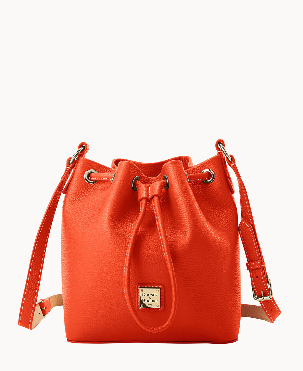 A bright orange leather bucket bag with a drawstring closure, gold-tone hardware, an adjustable shoulder strap, and a small square Dooney & Bourke logo plate on the front.