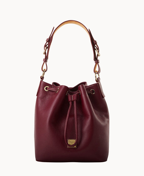 A burgundy leather drawstring bucket bag with a tan handle, gold-tone hardware, and a small gold logo plate on the front. The bag has a textured finish and a simple, elegant design.
