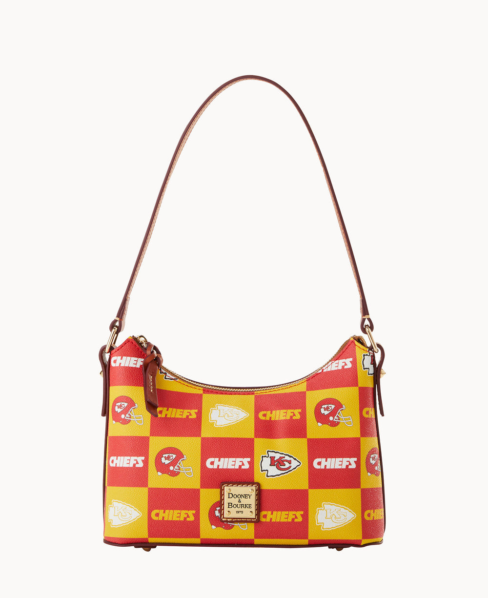 A handbag with a brown leather strap featuring a red and yellow checkerboard pattern with Kansas City Chiefs logos and the word CHIEFS. The front displays a gold Dooney & Bourke label.