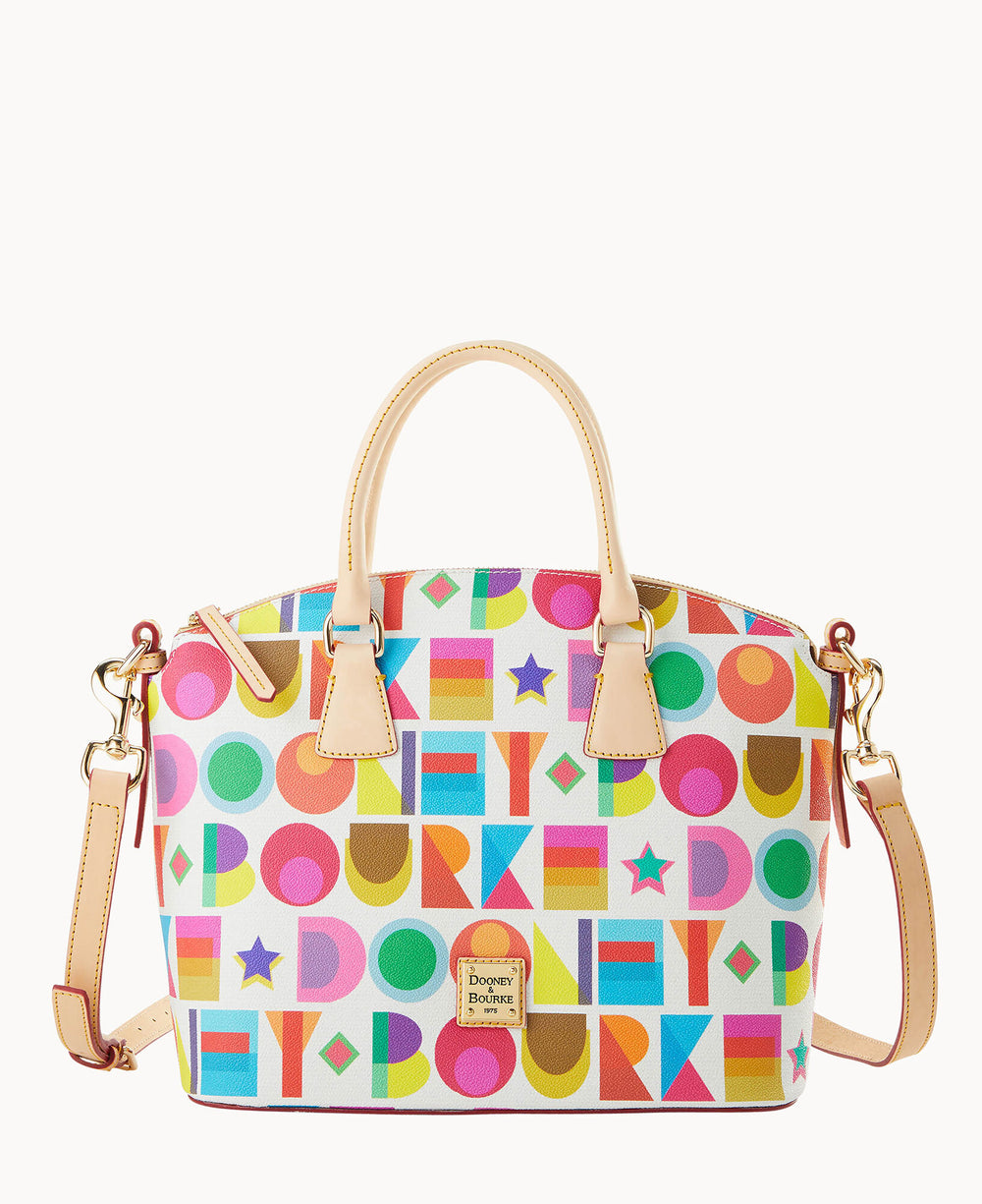A colorful Dooney & Bourke handbag with tan leather handles and strap, featuring a bold geometric pattern with circles, squares, and stars in various bright colors on a white background.