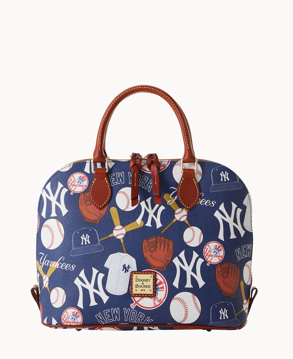 A blue Dooney & Bourke handbag featuring New York Yankees logos, baseballs, gloves, bats, and Yankees script, with brown leather handles and trim against a white background.