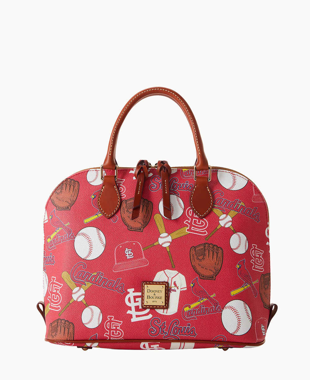 A red Dooney & Bourke handbag featuring St. Louis Cardinals logos and baseball-themed illustrations such as bats, balls, gloves, and hats, with brown leather handles and gold-tone hardware.