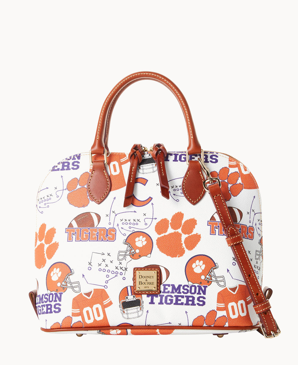 A white handbag with brown leather handles and orange accents, featuring Clemson Tigers logos, paw prints, football helmets, and football graphics in orange and purple.