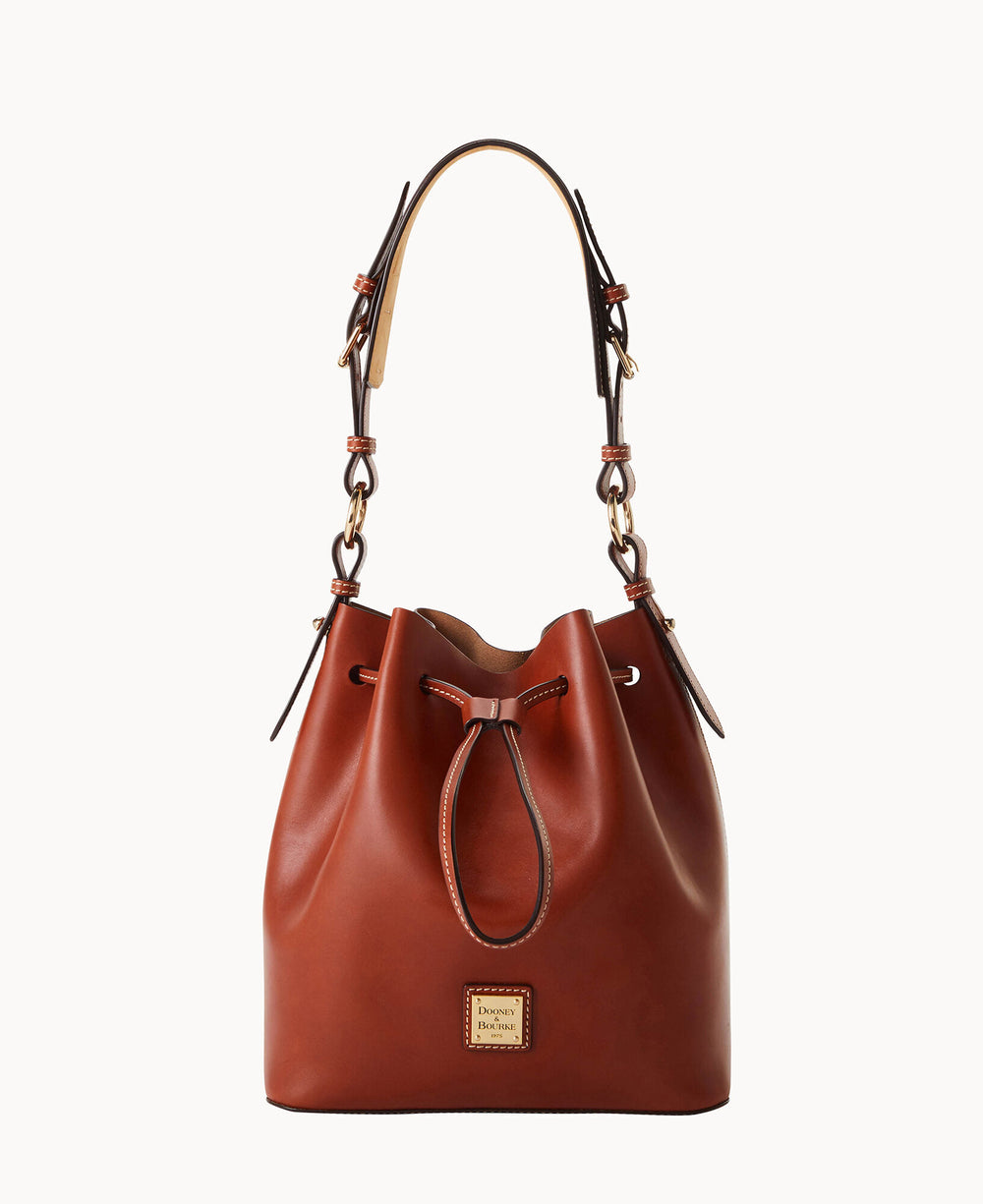 A brown leather bucket bag with a drawstring closure, gold-tone hardware, and an adjustable shoulder strap. The bag features a small rectangular brand logo patch on the front.