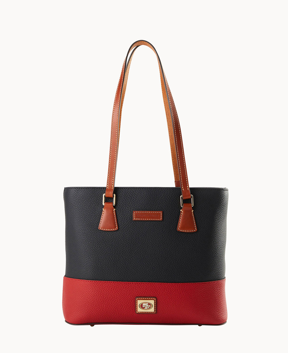 A two-tone leather tote bag with brown shoulder straps, a dark navy upper section, a red lower section, and a small logo patch on the front near the base.