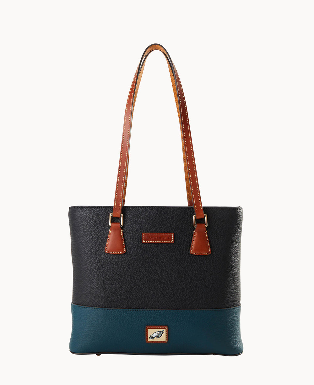 A black and teal leather tote bag with brown handles and trim, featuring a small rectangular patch with a bird logo on the front bottom center.