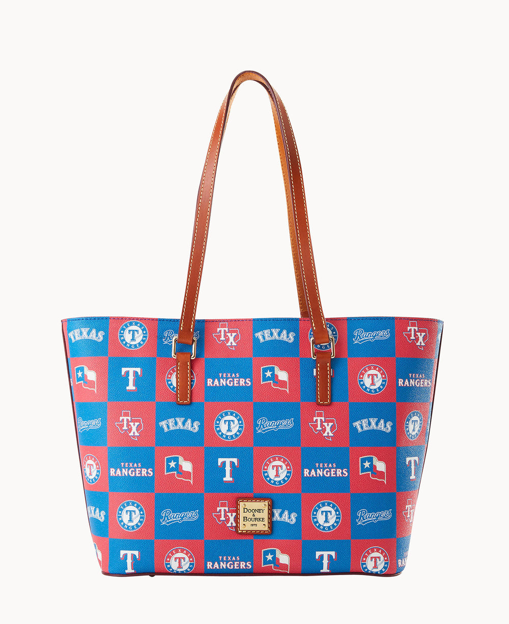 A tote bag with brown leather handles features a blue and red checkered pattern displaying Texas Rangers logos, Texas flags, and the word TEXAS. A Dooney & Bourke logo plate is on the front.