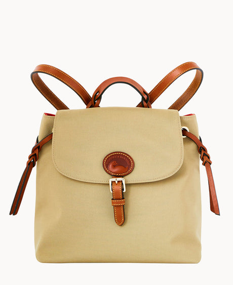 Tan canvas backpack with brown leather straps and trim, featuring a top handle, front flap with a buckle closure, and a rounded leather accent on the flap. The background is plain white.