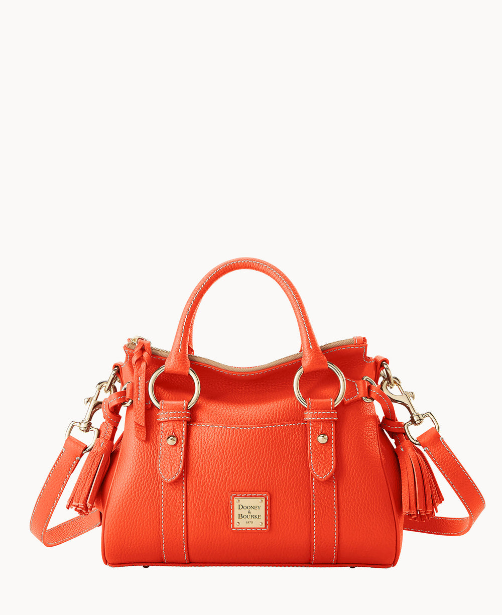 A bright orange leather handbag with gold hardware, double handles, a detachable shoulder strap, tassel accents, and a small Dooney & Bourke logo plate on the front.