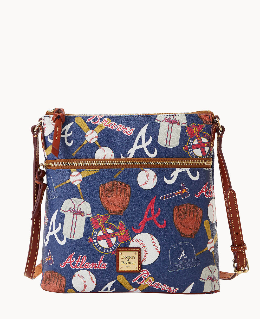 A blue crossbody bag decorated with Atlanta Braves baseball-themed illustrations, including bats, balls, gloves, jerseys, hats, and the team logo. The bag has brown leather accents and a gold Dooney & Bourke logo plate.