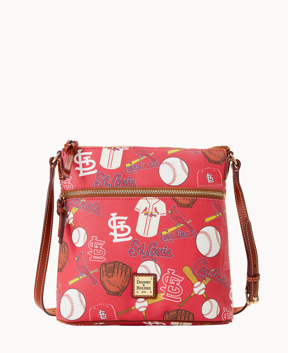 A red crossbody bag featuring St. Louis Cardinals logos, baseballs, baseball gloves, bats, jerseys, and caps in a repeating pattern with a brown adjustable strap and gold hardware.