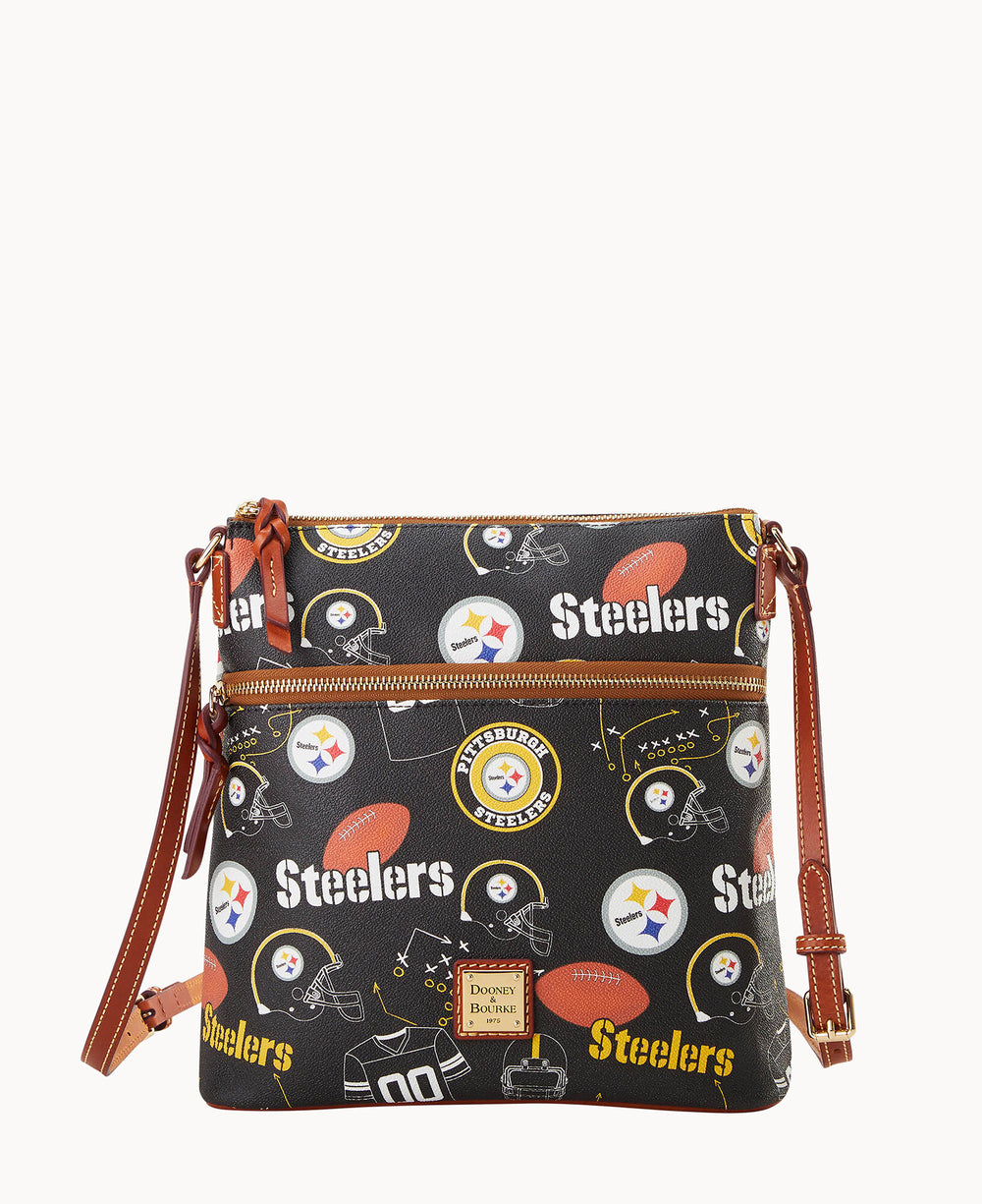 A black Dooney & Bourke crossbody bag featuring Pittsburgh Steelers logos, football graphics, and Steelers text, with brown leather straps and gold hardware.