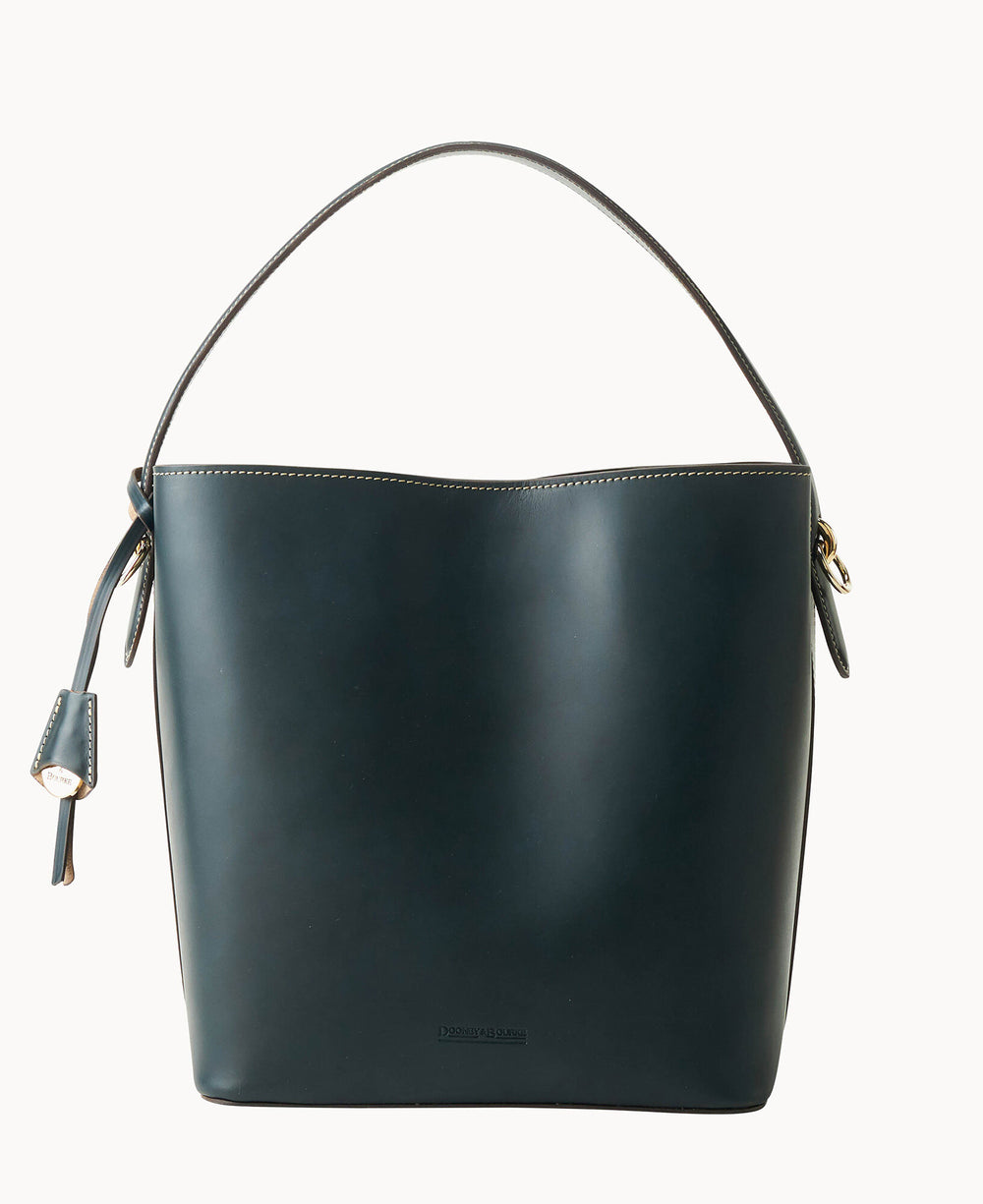 A dark leather bucket bag with a single handle, minimal stitching along the top edge, a side strap with a small tag, and a structured, smooth finish.