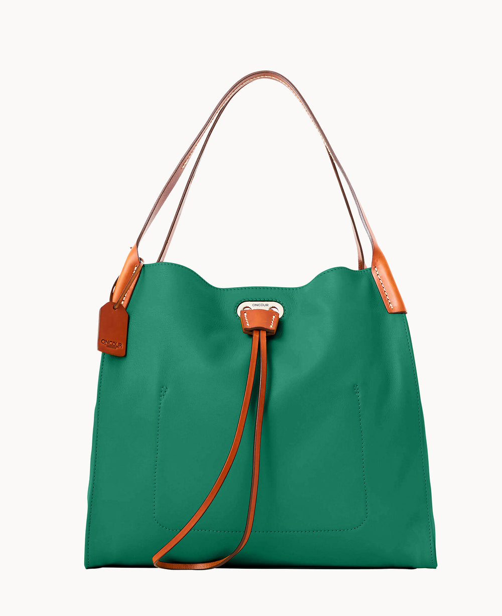 A green tote bag with brown leather handles and accents, featuring a brown leather tag and drawstring detail on the front. The background is plain white.