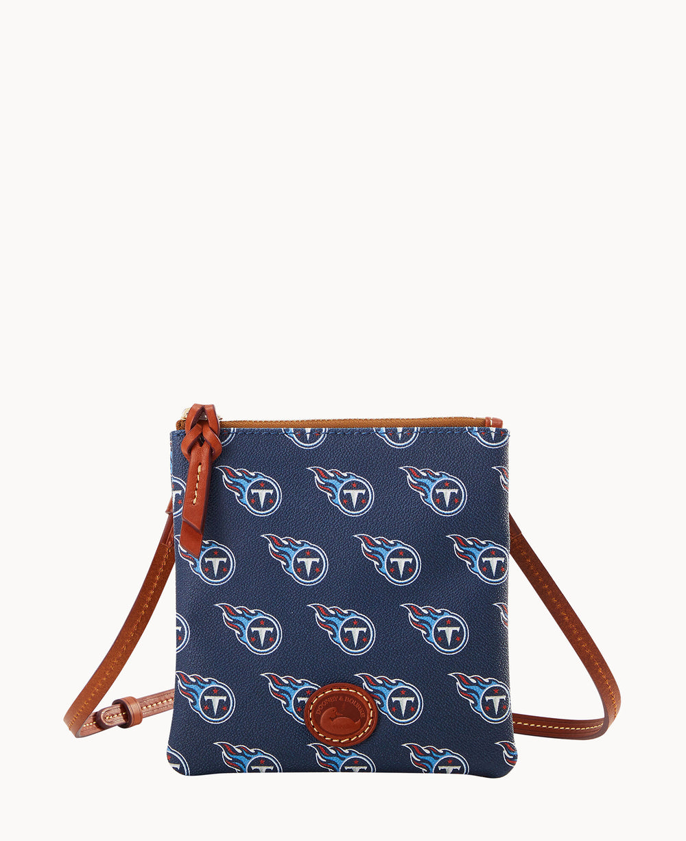 A small navy blue crossbody bag with brown leather trim and strap, featuring a repeating Tennessee Titans logo pattern and a leather logo patch on the front.