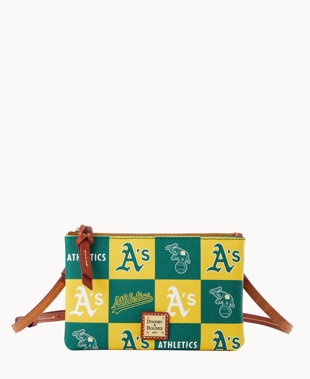 A small crossbody bag with a checkered green, yellow, and white pattern featuring various Oakland Athletics logos. The bag has a brown leather strap and a Dooney & Bourke label on the front.