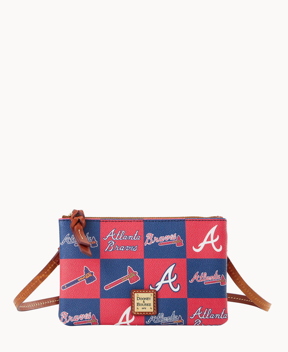 A small crossbody bag with a blue and red checker pattern featuring the Atlanta Braves logos, tomahawks, and Atlanta Braves text, with a tan strap and a Dooney & Bourke label on the front.