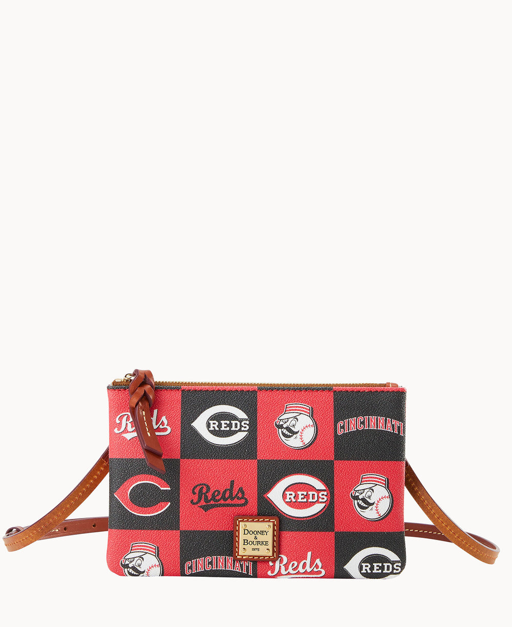 A small crossbody bag with a brown strap, featuring a red and black checkerboard pattern and Cincinnati Reds baseball team logos and text. The bag has a gold Dooney & Bourke label on the front.