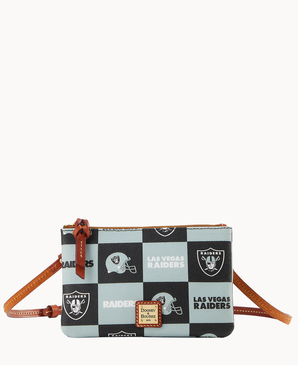 A small crossbody bag with a brown strap featuring a black and white checkered pattern with Las Vegas Raiders text, team logos, and helmets. A Dooney & Bourke logo plaque is on the front.