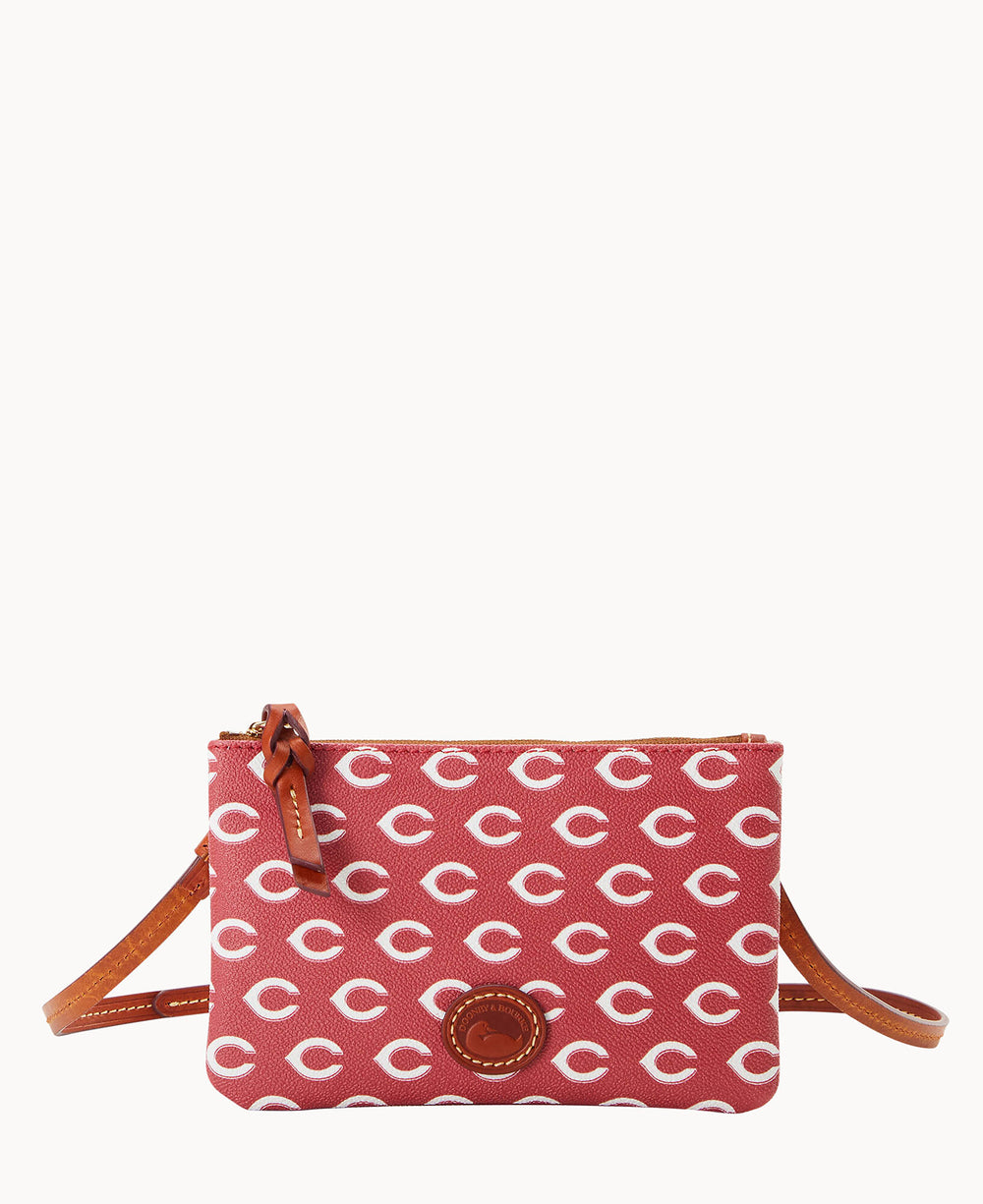 A small red crossbody bag with a repeating white C pattern, brown leather trim, and an adjustable leather strap. The bag has a zipper closure and a round leather logo patch on the front.