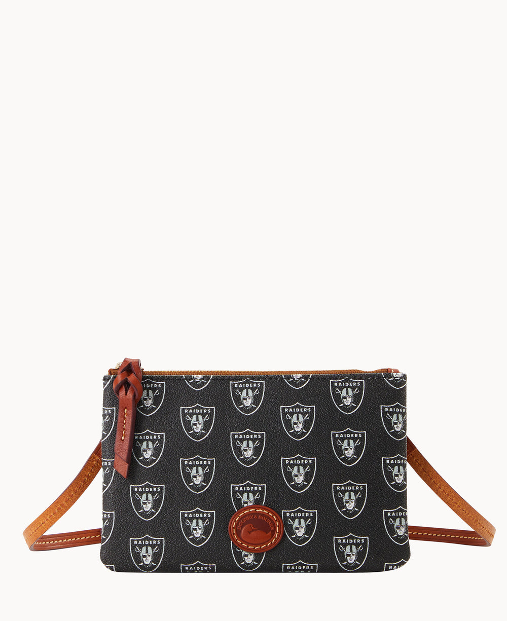 A small black crossbody bag with brown leather strap and trim, decorated with repeated white Raiders logos and a brown leather patch on the front.