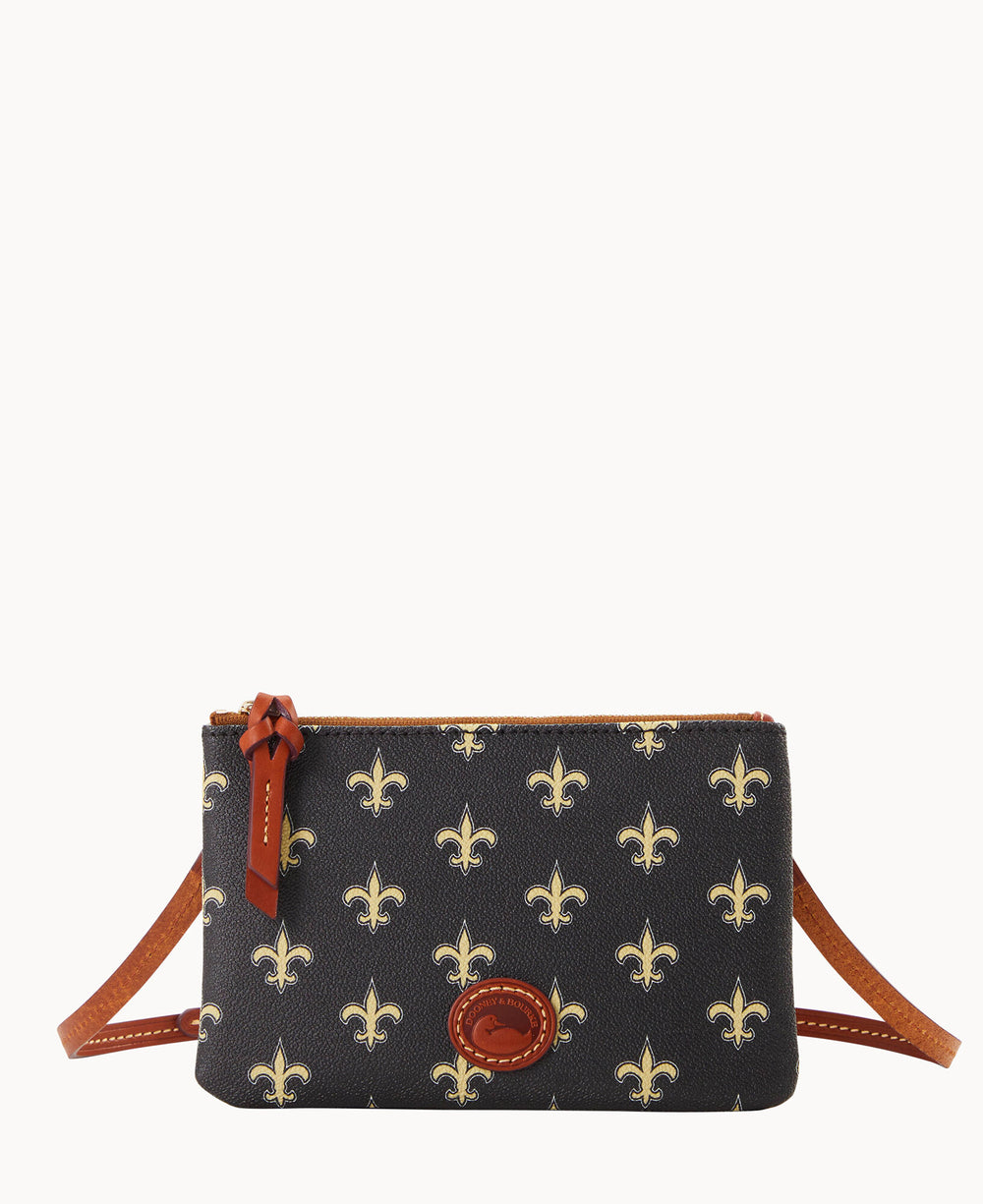 A small crossbody bag with brown leather trim and strap, featuring a dark background with a repeating gold fleur-de-lis pattern and a leather logo patch on the front.