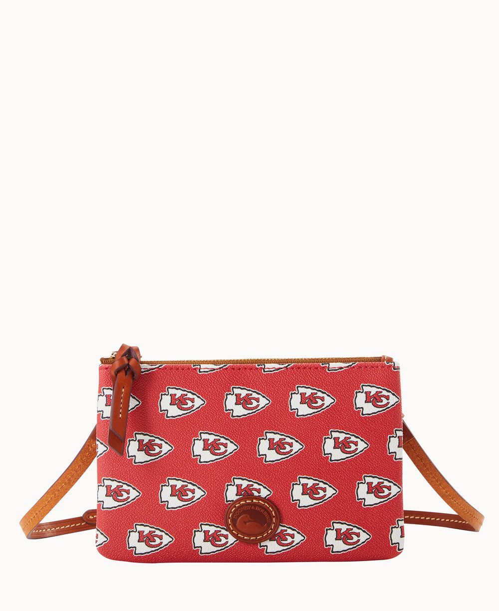 A red crossbody bag with brown leather accents, featuring an all-over pattern of the Kansas City Chiefs football team logo and a zippered top.